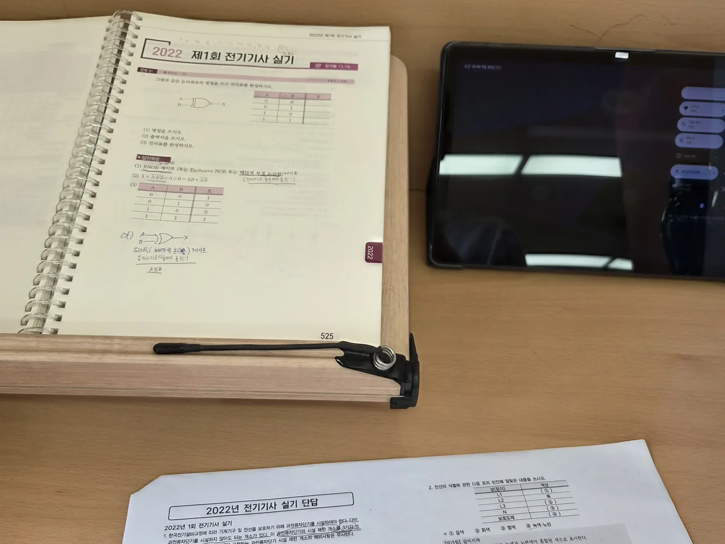 책상 위 인증샷 예시. 펼친 문제집과 손글씨 필기가 있는 답안지, 태블릿이 한 장에 담겨 있다